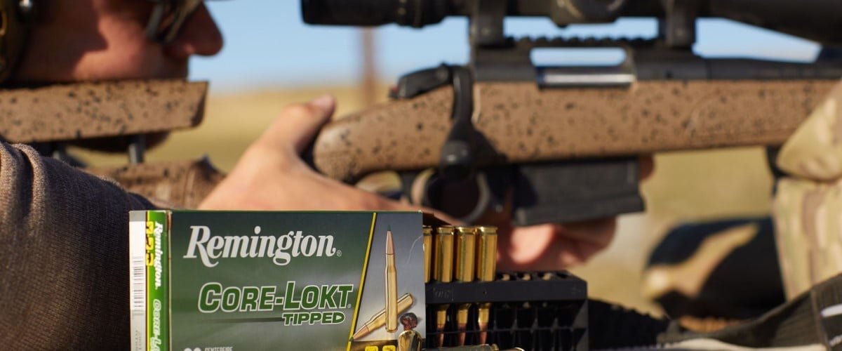 shooter looking down a rifle scope with a box of Core-Lokt Tipped box and cartridges